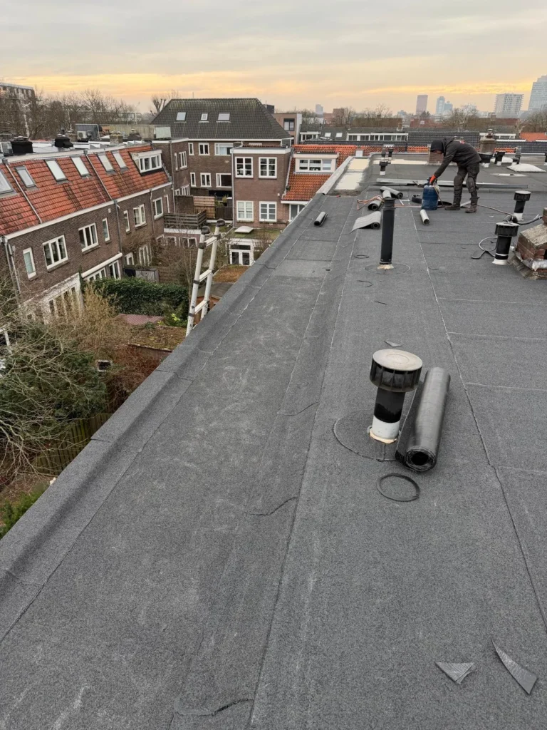 Dakdekker brandt bitumen dakbedekking op een plat dak in Lunteren