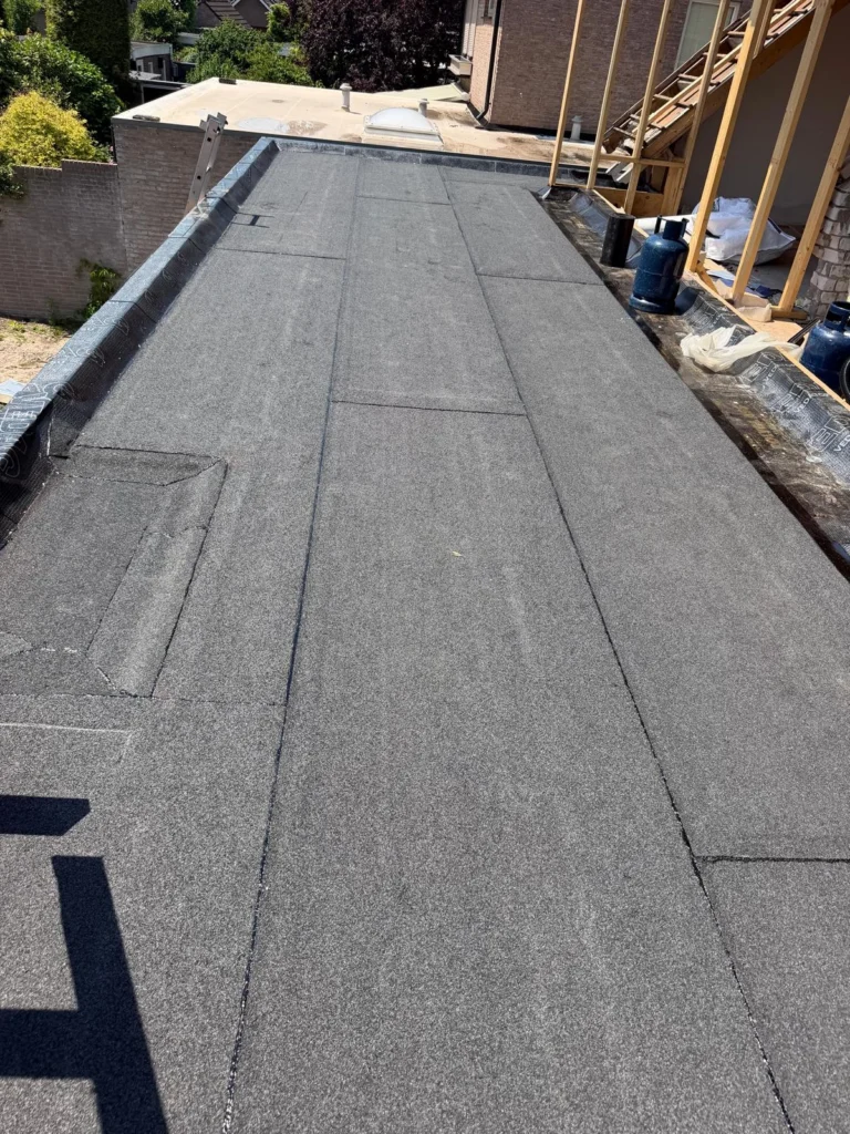 Nieuw bitumen plat dak naast een houten dakopbouw in aanbouw in Lunteren