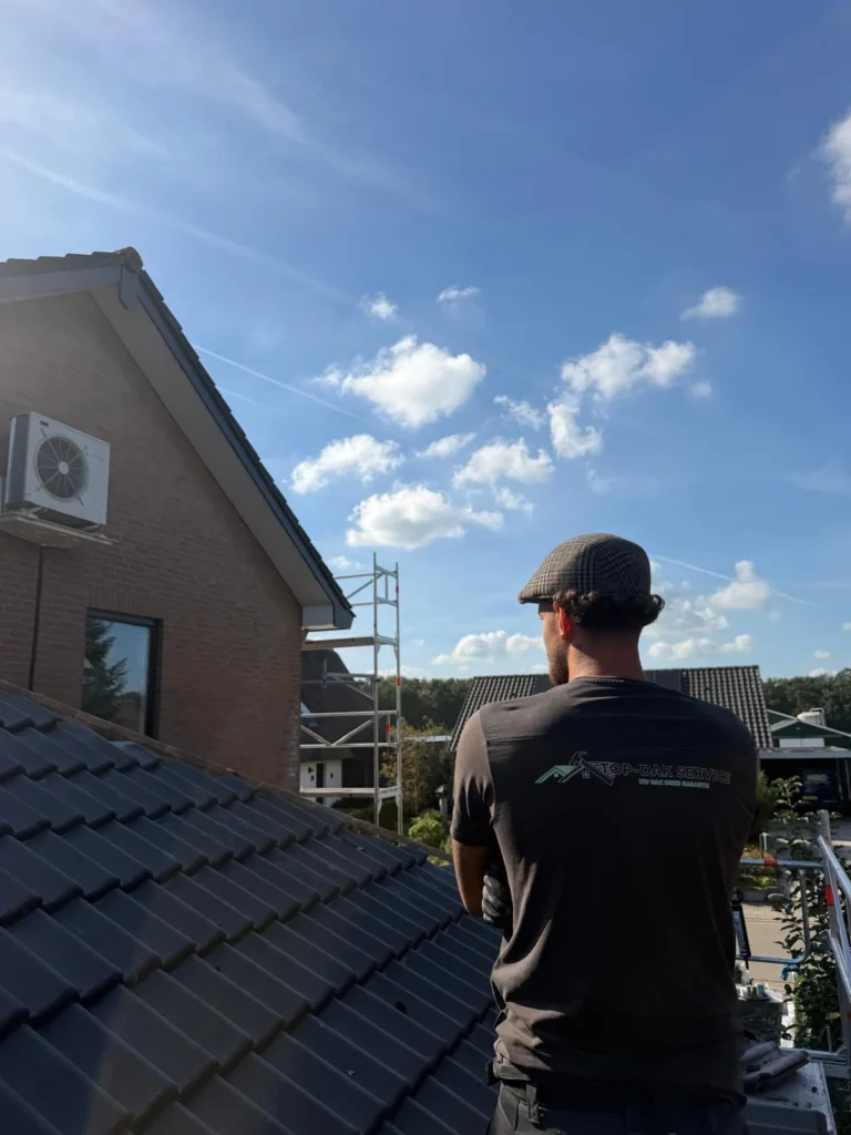 Dakdekker staat op de steiger en kijkt over het pannendak in Lunteren