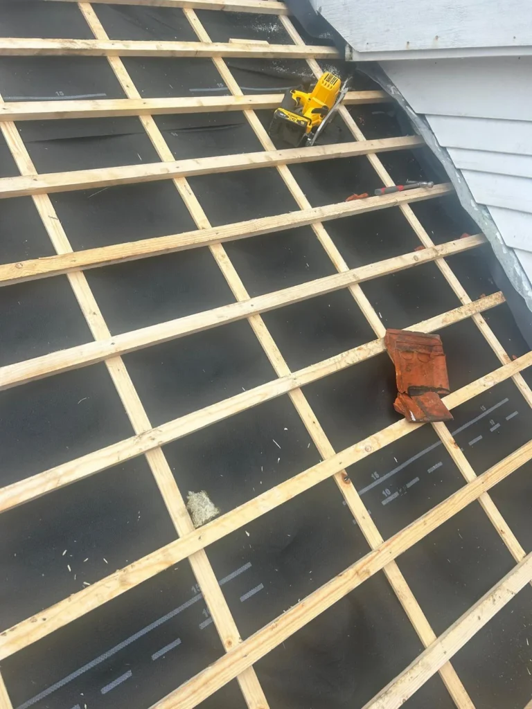 Nieuwe panlatten op folie met een oude dakpan en cirkelzaag in Lunteren