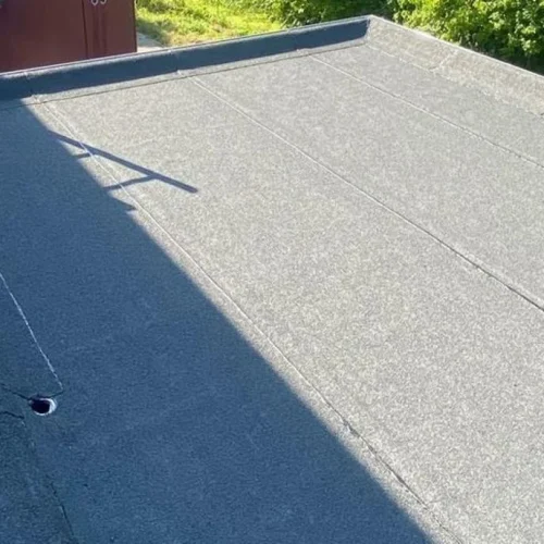 Afgewerkt bitumen plat dak op een aanbouw met strakke dakrand in Lunteren
