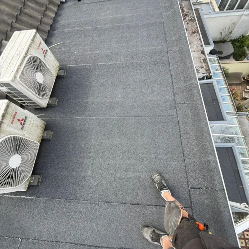 Afgewerkt bitumen plat dak met airco-units op steunen in Lunteren